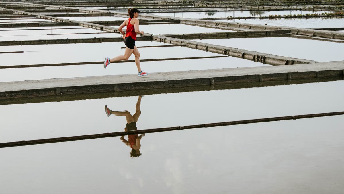 A lone runner races across a reflective surface bridge, showcasing endurance and determination.